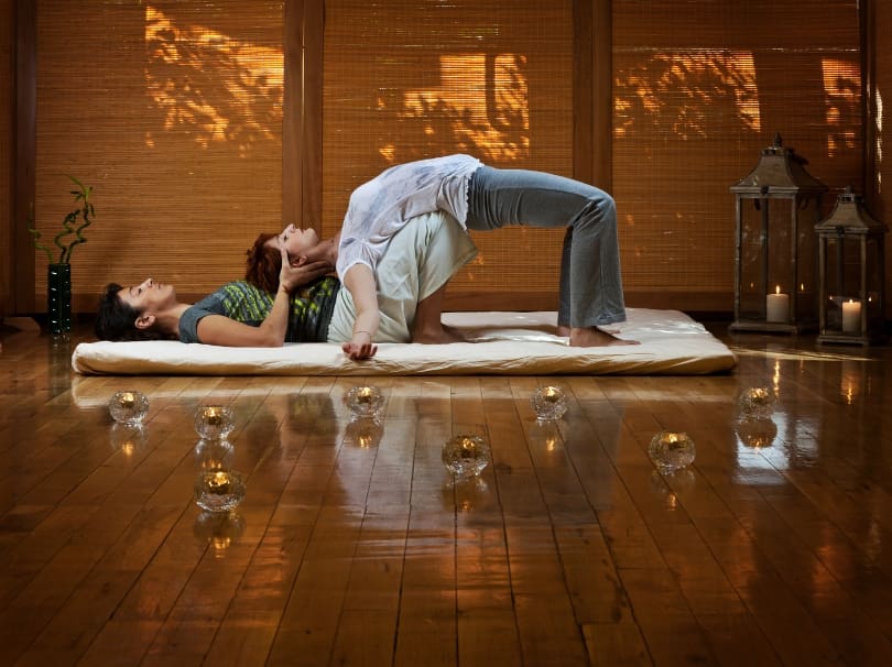 A man and woman doing yoga on the floor.