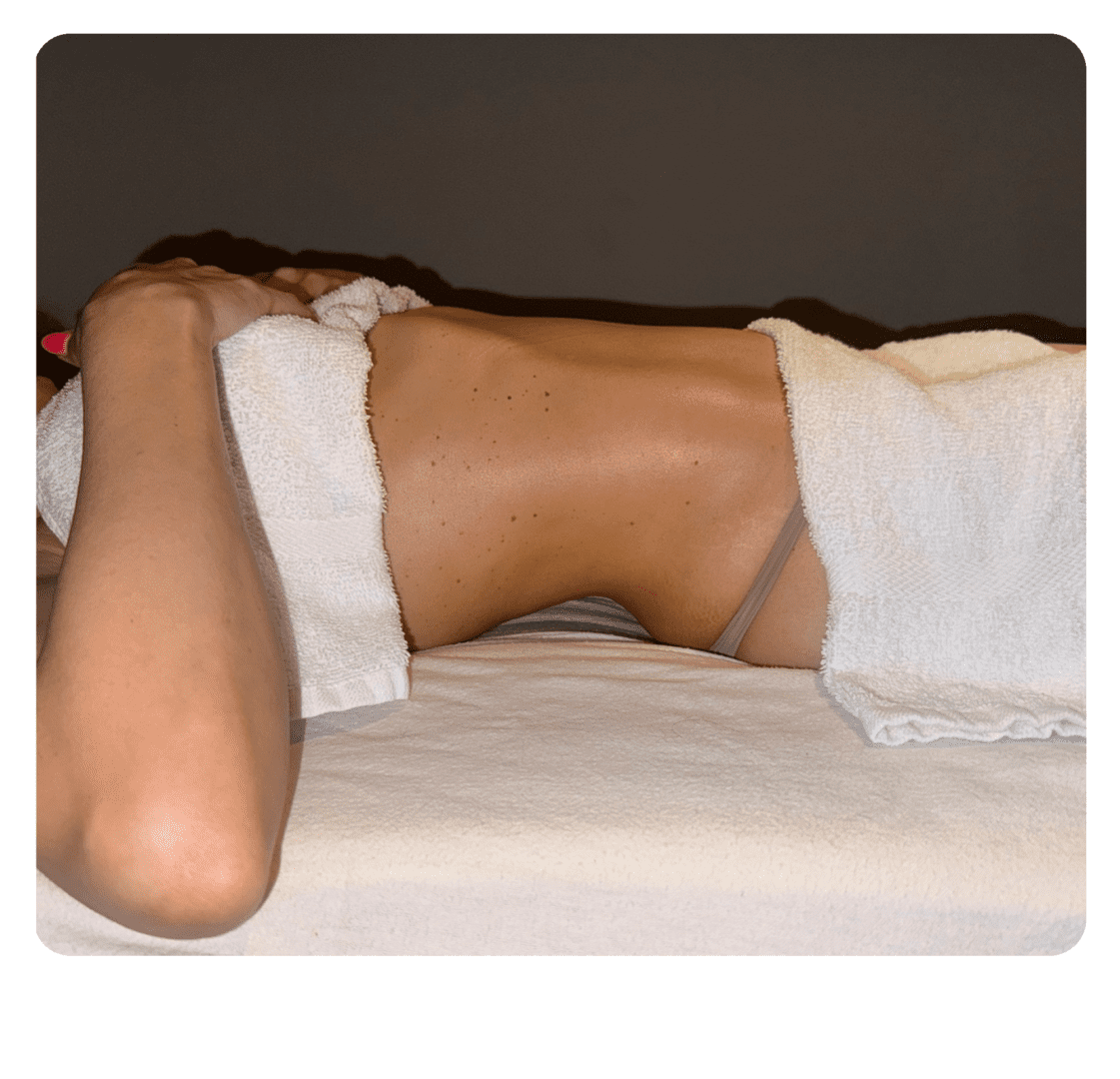 A woman laying on top of a bed with white sheets.